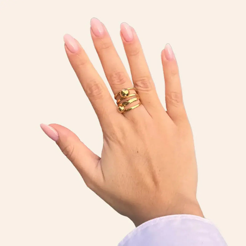 Main ornée de la bague Ankara dorée en acier inoxydable, bague élégante et originale.