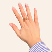 Main portant la bague Antalya en acier inoxydable doré avec pendentifs délicats et pierres scintillantes.