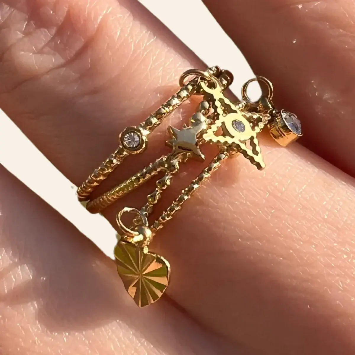 Zoom sur la bague Antalya en acier inoxydable doré, mettant en valeur les pendentifs raffinés et les oxydes de zirconium étincelants.