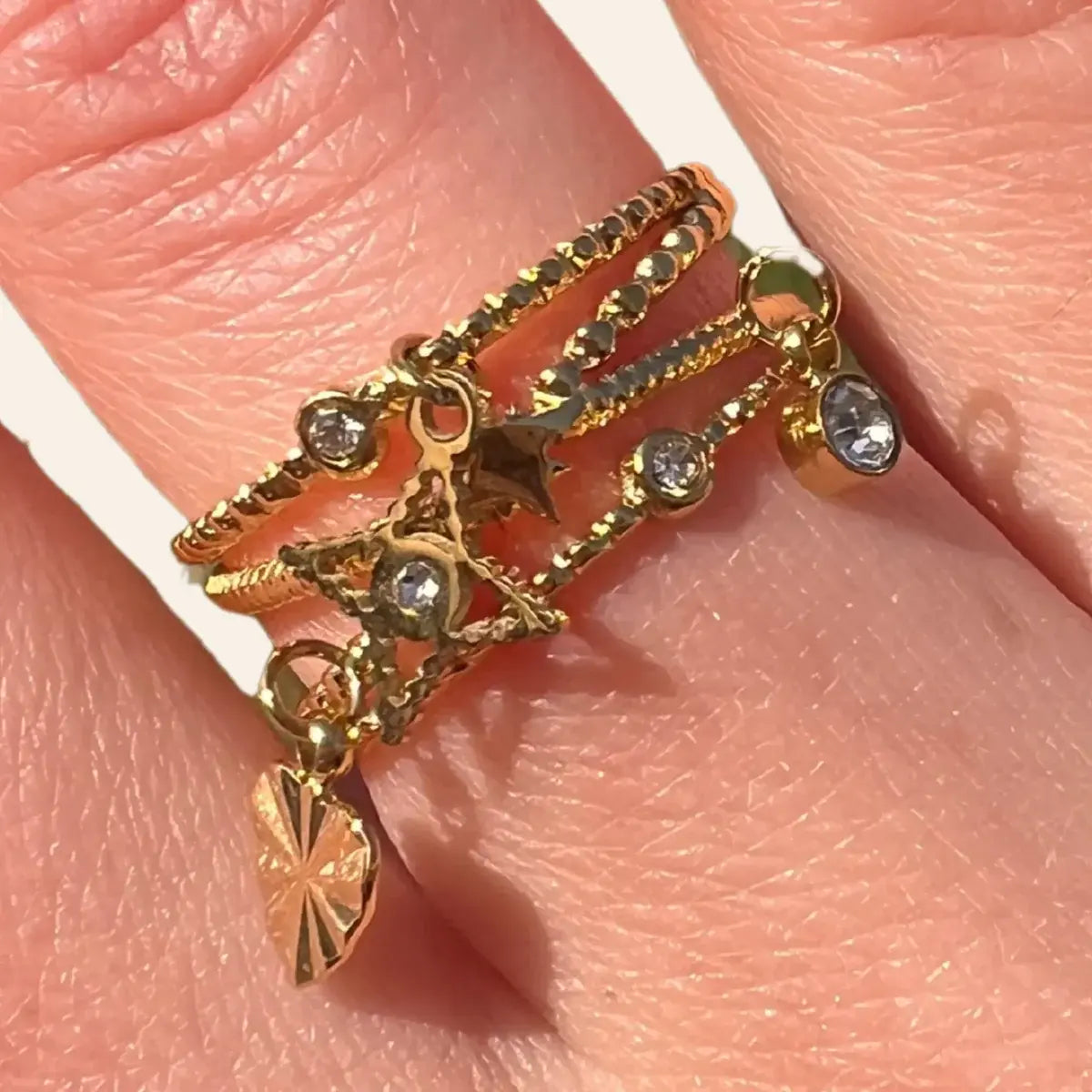 Zoom sur la bague Antalya en acier inoxydable doré, mettant en valeur les pendentifs raffinés et les oxydes de zirconium étincelants.