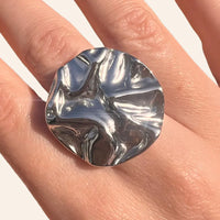 Gros plan sur la bague Berlin argentée, détaillant sa forme ronde et ses courbes audacieuses, évoquant l’architecture contemporaine de Berlin.