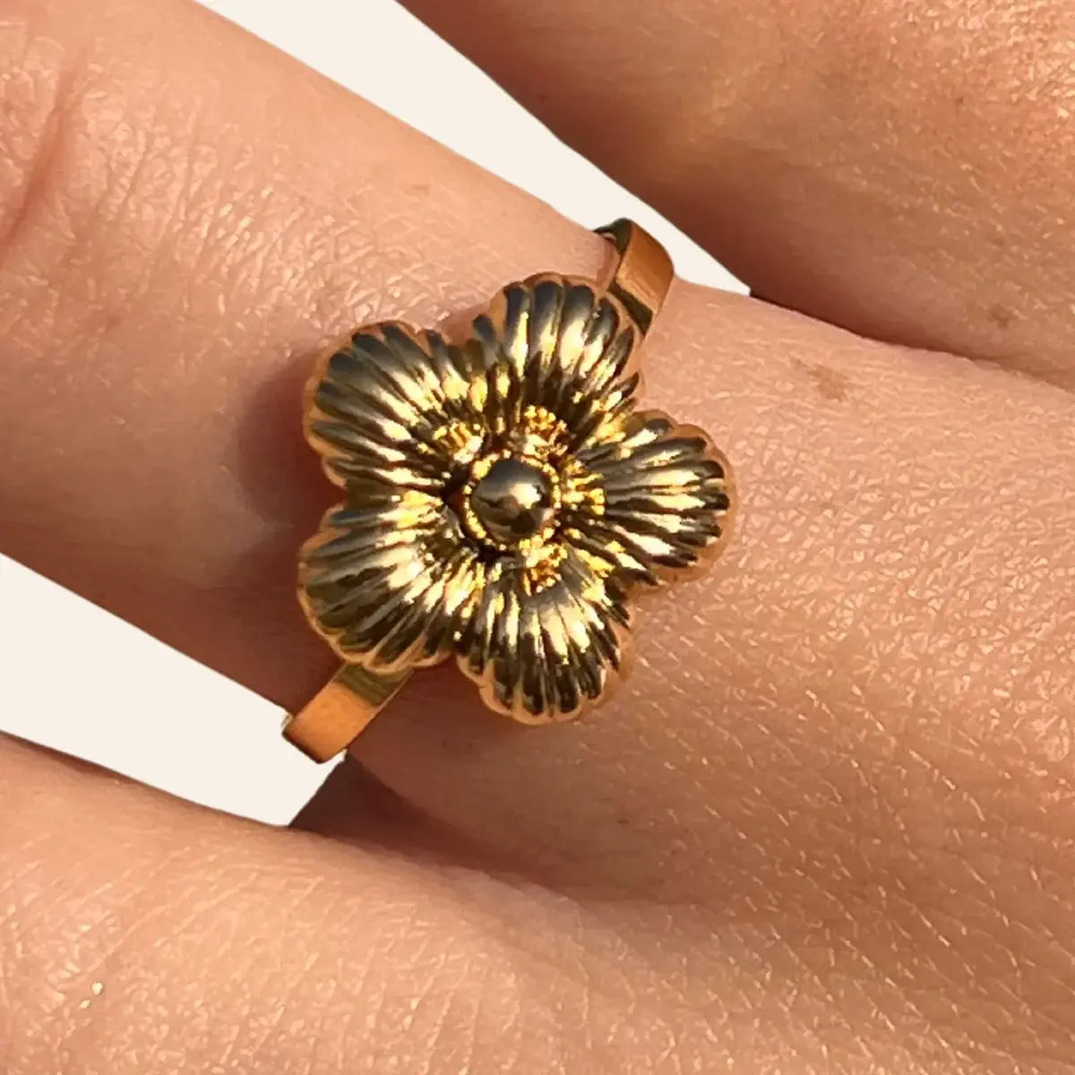 Zoom sur la bague Florence dorée en acier inoxydable, mettant en valeur la fleur délicate en relief, évoquant l’élégance des jardins florentins et l'art classique.