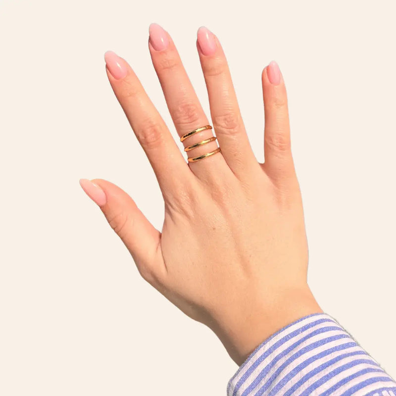 Main portant la bague Gizeh dorée en acier inoxydable, bijou élégant avec trois traits espacés pour un look moderne et raffiné.