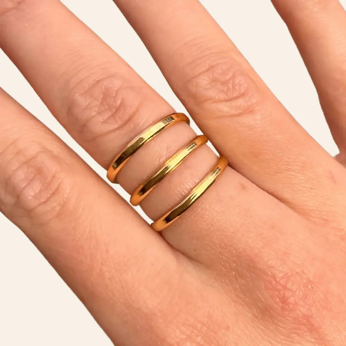 Zoom sur la bague Gizeh dorée en acier inoxydable, mettant en valeur les trois traits espacés et la finition brillante.