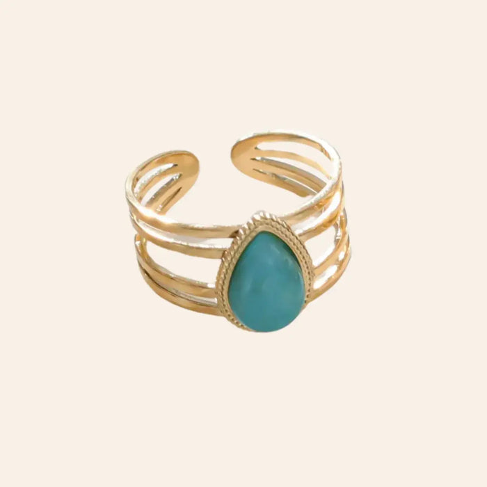 Bague Jaipur en acier inoxydable doré avec une goutte centrale bleue, design élégant et moderne, présentée seule sur fond neutre.
