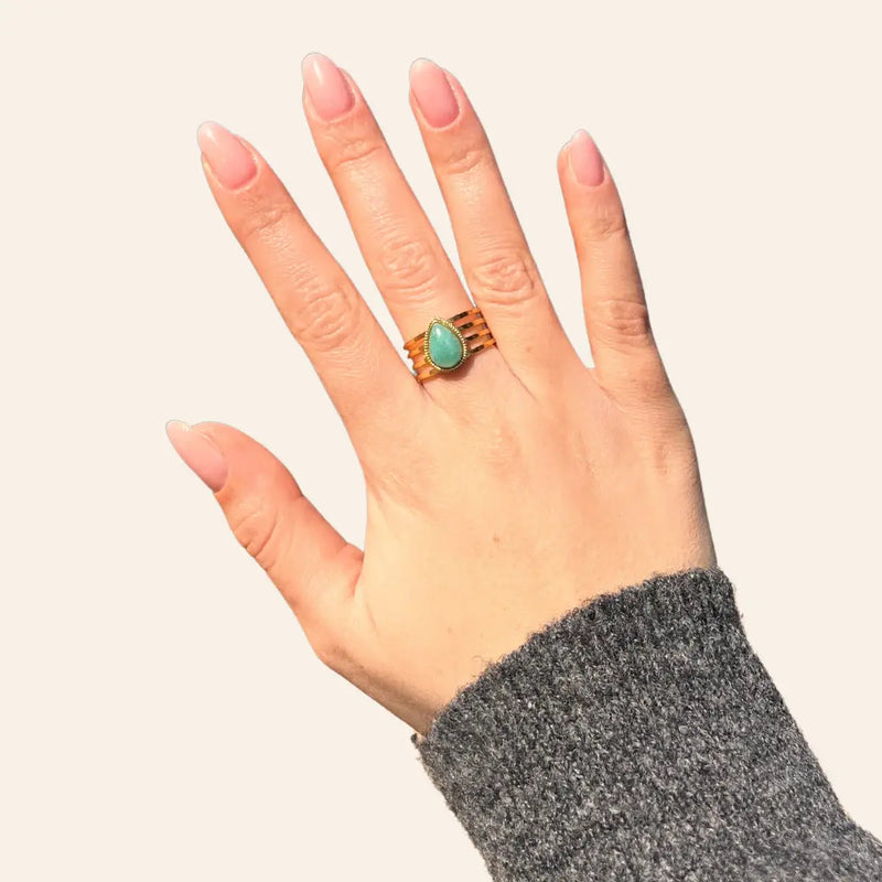 Main féminine portant la bague Jaipur dorée avec goutte bleue, bijou raffiné et coloré au design tendance.