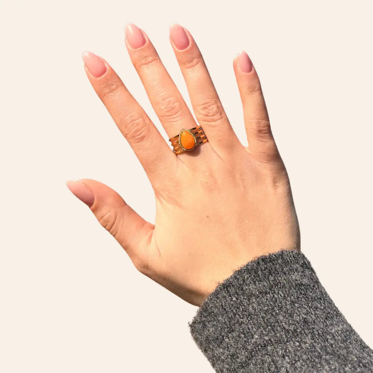Bague Jaipur en acier inoxydable doré avec goutte orange au centre, bijou coloré et élégant porté sur le doigt.