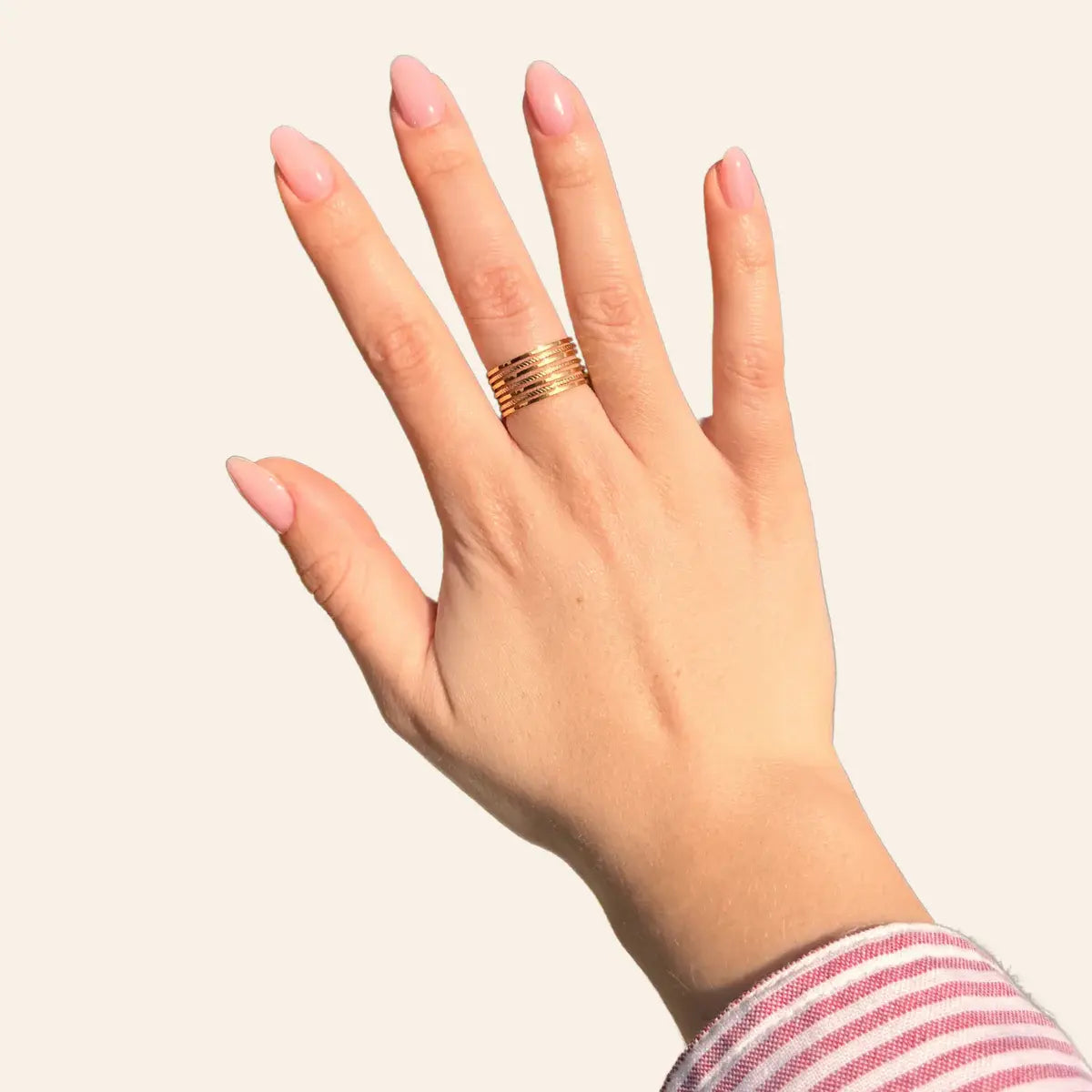 Main ornée de la bague Lagos en acier inoxydable doré, bijou tendance et élégant.