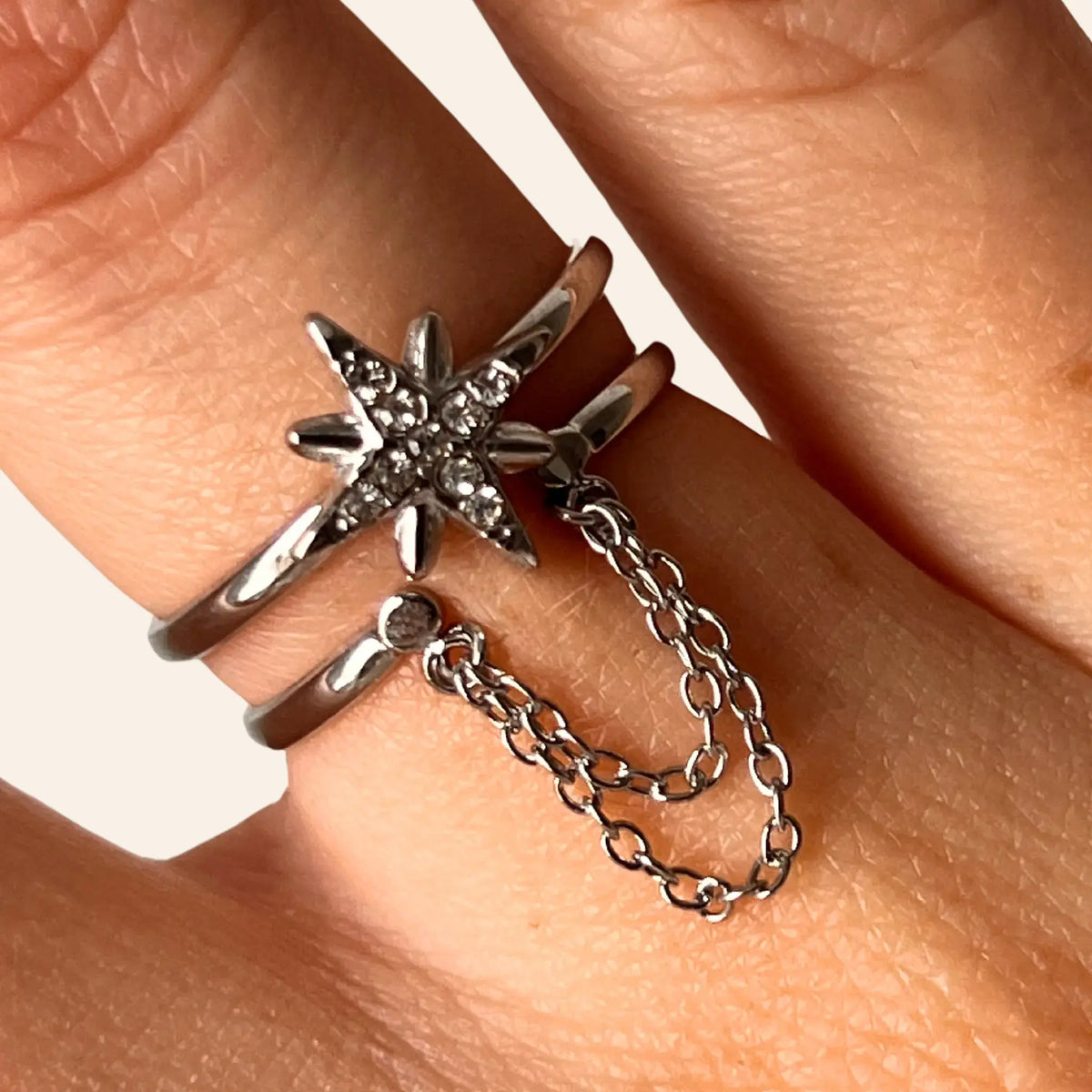 Gros plan sur la bague Londres argentée, détaillant l’étoile scintillante et la chaîne suspendue, symbolisant l’élégance et l’avant-garde de Londres.