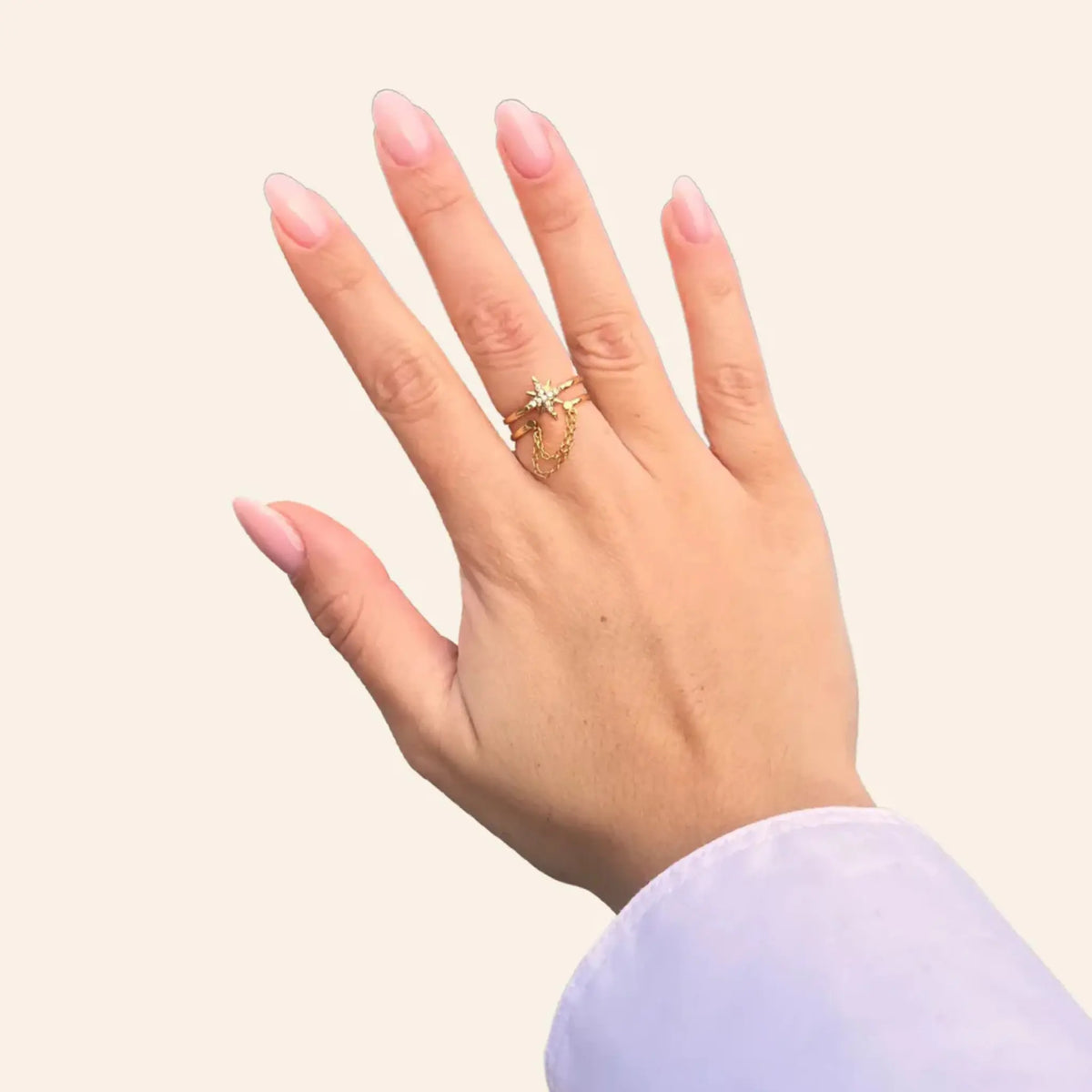 Bague Londres dorée portée, design unique avec étoile scintillante et chaîne suspendue, ajoutant une touche d’élégance urbaine et contemporaine à votre look.