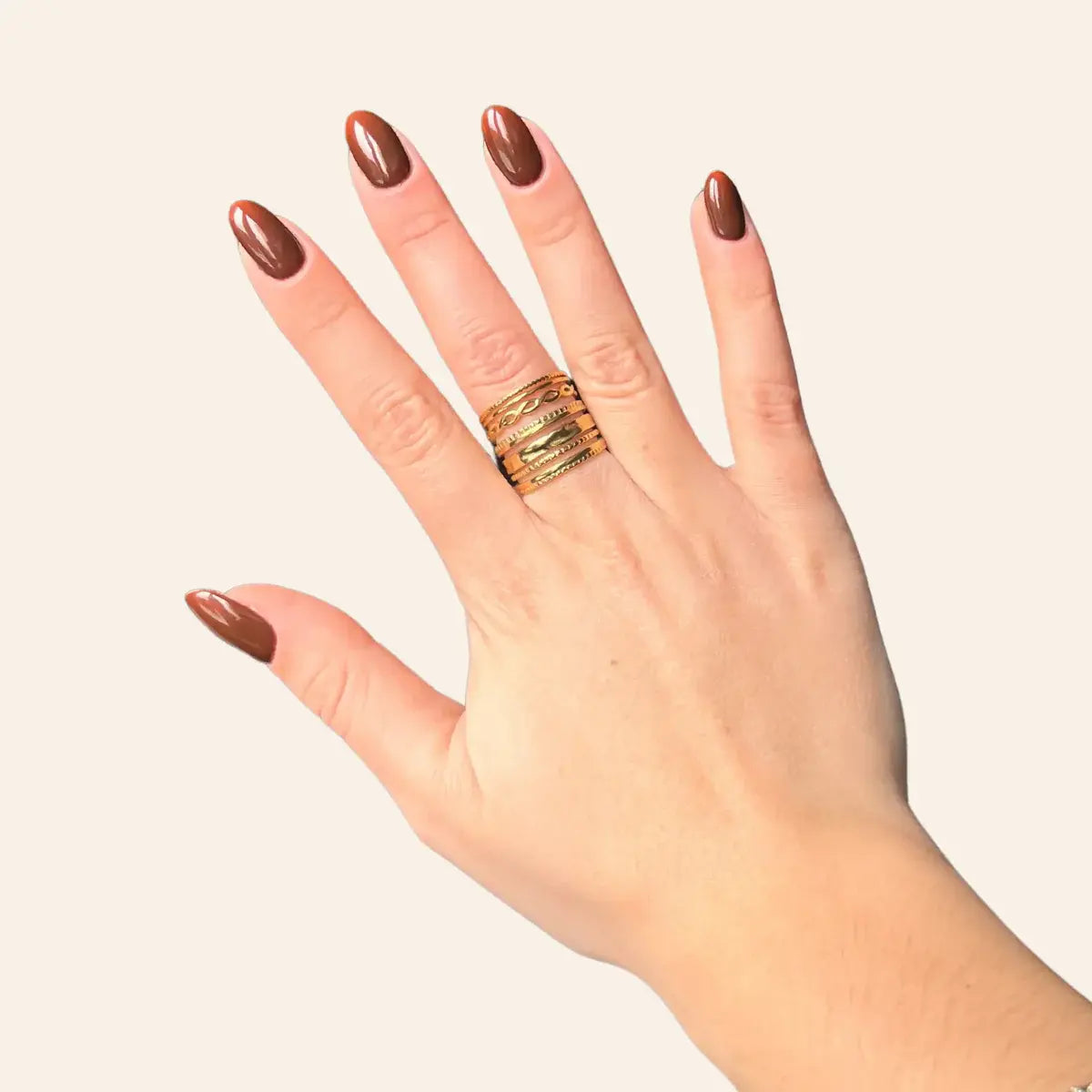 Main féminine portant la bague Rio dorée en acier inoxydable, bijou large avec lignes ondulées et finition brillante.