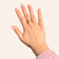 Main féminine portant la bague Sofia en acier inoxydable doré, étoile centrale sertie de strass scintillants.