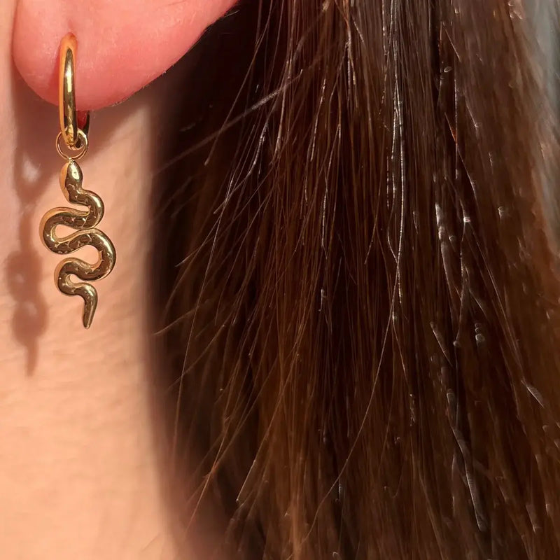 Boucles Jakarta dorées portées, bijou élégant avec serpent suspendu, ajoutant une touche audacieuse et contemporaine.