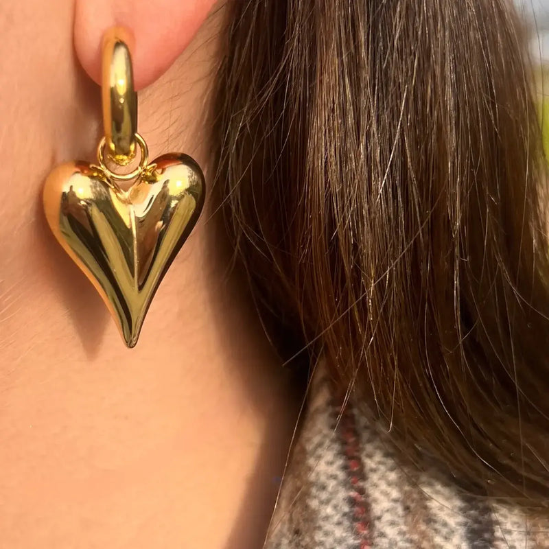 Boucles Prague dorées portées, bijou audacieux avec un gros cœur suspendu, parfait pour un look romantique et moderne.