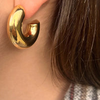 Boucles Vérone dorées portées, créoles épaisses en acier inoxydable, ajoutant une touche audacieuse et élégante à votre look.