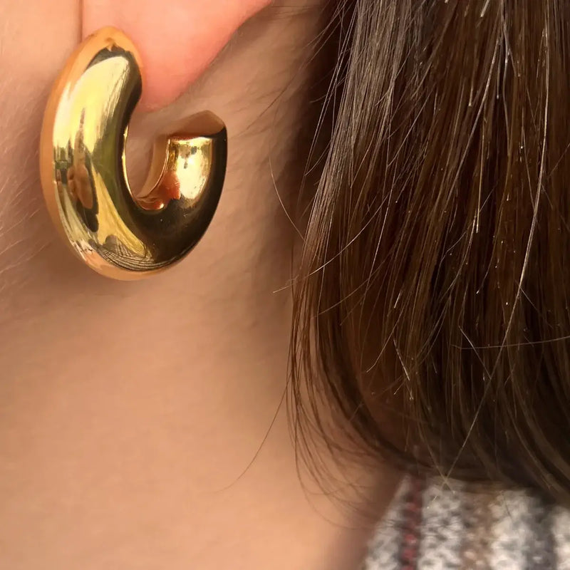 Boucles Vérone dorées portées, créoles épaisses en acier inoxydable, ajoutant une touche audacieuse et élégante à votre look.