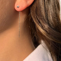 Boucles d’oreilles Canberra en acier inoxydable argenté portées, chaînes fines et petites étoiles suspendues, parfaites pour une touche subtile d’élégance.