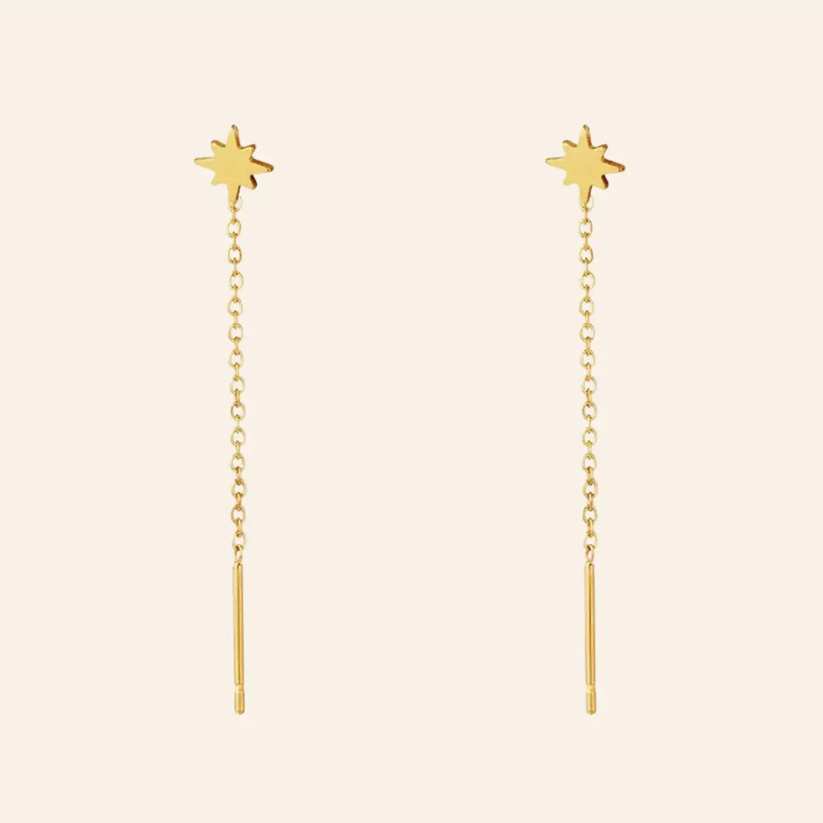 Boucles d’oreilles Canberra en acier inoxydable doré, chaînes délicates et petits pendentifs en forme d'étoiles, design moderne et chic, présentées seules sur fond neutre.
