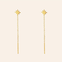 Boucles d’oreilles Canberra en acier inoxydable doré, chaînes délicates et petits pendentifs en forme d'étoiles, design moderne et chic, présentées seules sur fond neutre.