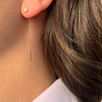 Boucles d’oreilles Canberra dorées portées, chaînes fines avec pendentifs étoiles, ajoutant une touche de raffinement et de féminité à votre look quotidien ou habillé.