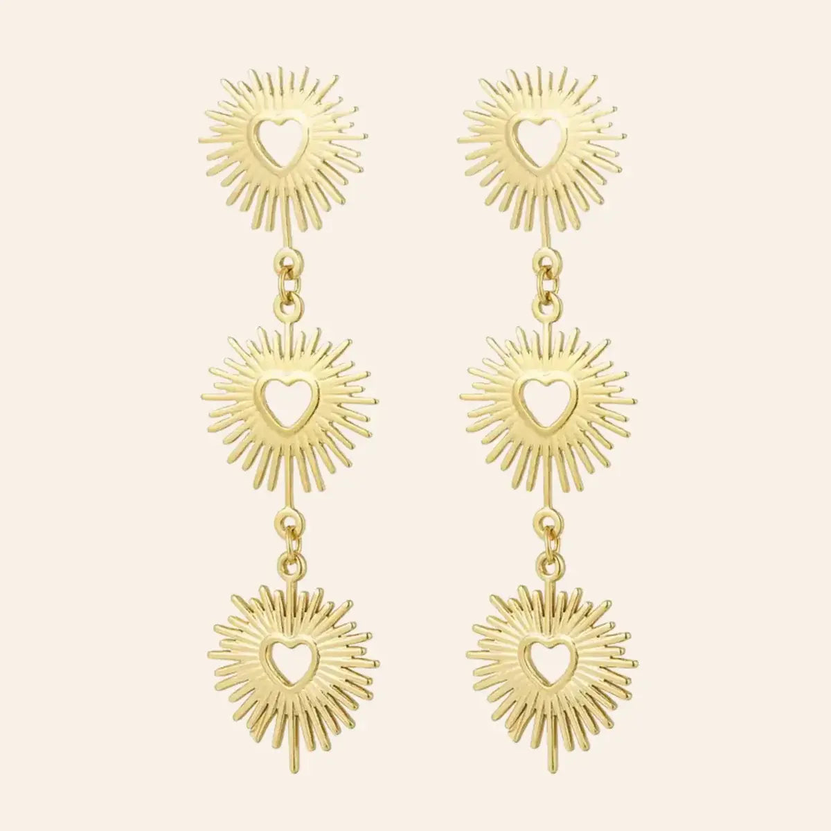 Boucles d'oreilles Dubaï en acier inoxydable doré, pendentifs solaires sculptés et cœurs ajourés, design opulent et moderne, présenté seul sur fond neutre.
