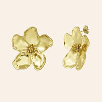 Boucles d’oreilles Nairobi en acier inoxydable doré, forme florale délicate avec chaque pétale soigneusement travaillé, incarnant l’élégance et la grâce de la floraison, présentées seules sur fond neutre.