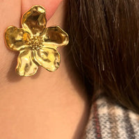 Boucles d’oreilles Nairobi dorées portées, design floral raffiné, structuré symbolisant la beauté vibrante et naturelle de Nairobi, ajoutant une touche élégante à votre look.