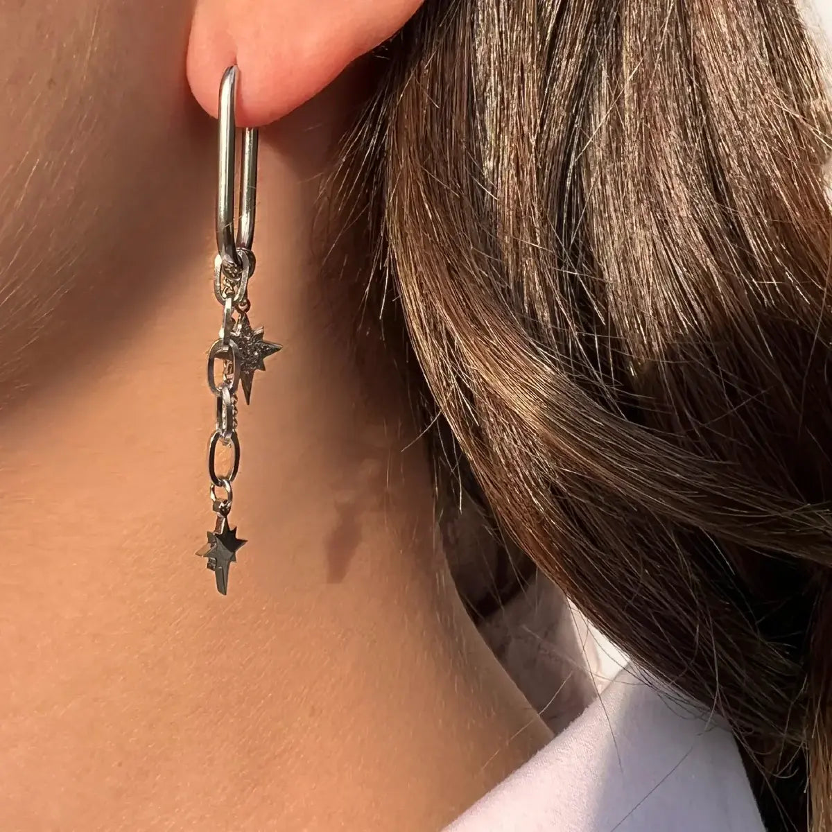 Boucles d’oreilles Oslo en acier inoxydable argenté portées, design minimaliste avec pendentifs étoilés, ajoutant une touche d’élégance inspirée de l’esthétique nordique.