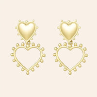 Boucles d’oreilles Paris en acier inoxydable doré, design élégant avec un cœur plein et un cœur ouvert en dessous, ornés de petites perles délicates, présenté seul sur fond neutre.