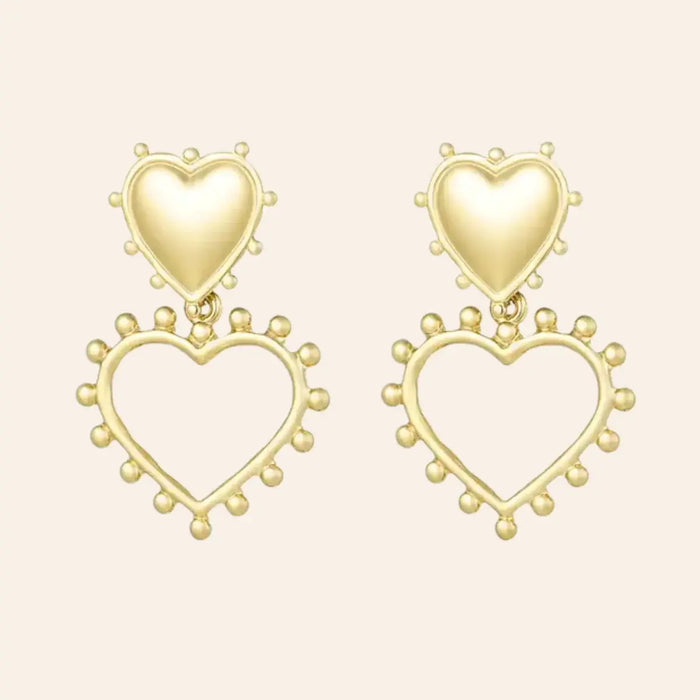 Boucles d’oreilles Paris en acier inoxydable doré, design élégant avec un cœur plein et un cœur ouvert en dessous, ornés de petites perles délicates, présenté seul sur fond neutre.