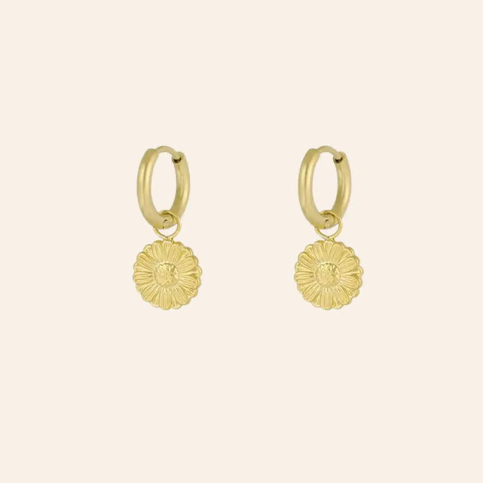 Boucles d’oreilles Pretoria en acier inoxydable doré, petite fleur suspendue, design délicat et élégant, présenté seul sur fond neutre.
