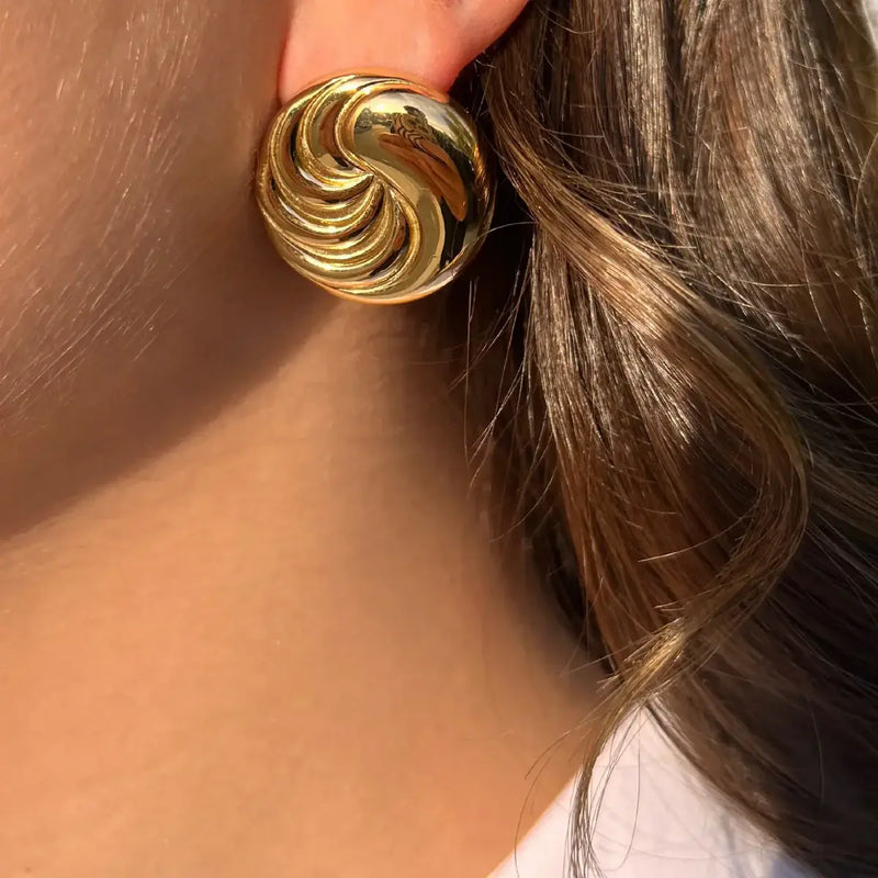 Boucles d’oreilles Séoul dorées portées, design moderne rond et audacieux capturant l'harmonie entre tradition et futur de la capitale coréenne.