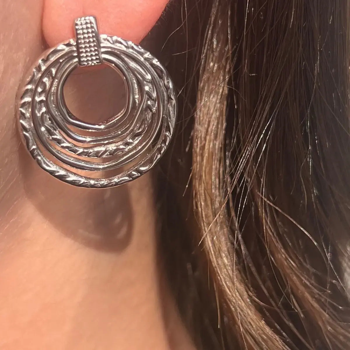 Boucles d’oreilles Séville en acier inoxydable argenté portées, accessoire chic et lumineux.