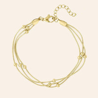 Bracelet Barcelone en acier inoxydable doré, fines chaînes entrelacées avec petites perles délicates, présenté seul sur fond neutre.