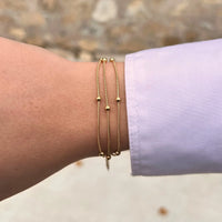 Bracelet Barcelone doré porté, bijou moderne et sophistiqué avec chaînes entrelacées et perles, parfait pour compléter n'importe quel look.