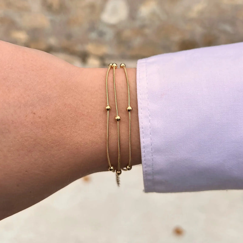 Bracelet Barcelone doré porté, bijou moderne et sophistiqué avec chaînes entrelacées et perles, parfait pour compléter n'importe quel look.