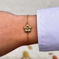 Bracelet Florence doré porté, fleur délicate apportant une touche de féminité et de raffinement à votre poignet, ajoutant de la grâce à chaque mouvement.