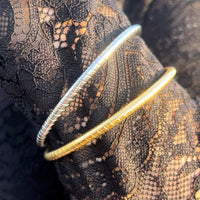 Poignet féminin portant le bracelet Jonc Quito doré et argenté, bijou simple avec des petits traits décoratifs, élégant et moderne.