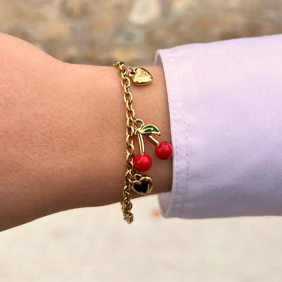 Bracelet Lisbonne doré porté, charms en forme de cœurs et cerise rouge vif apportant fraîcheur et légèreté à votre poignet.