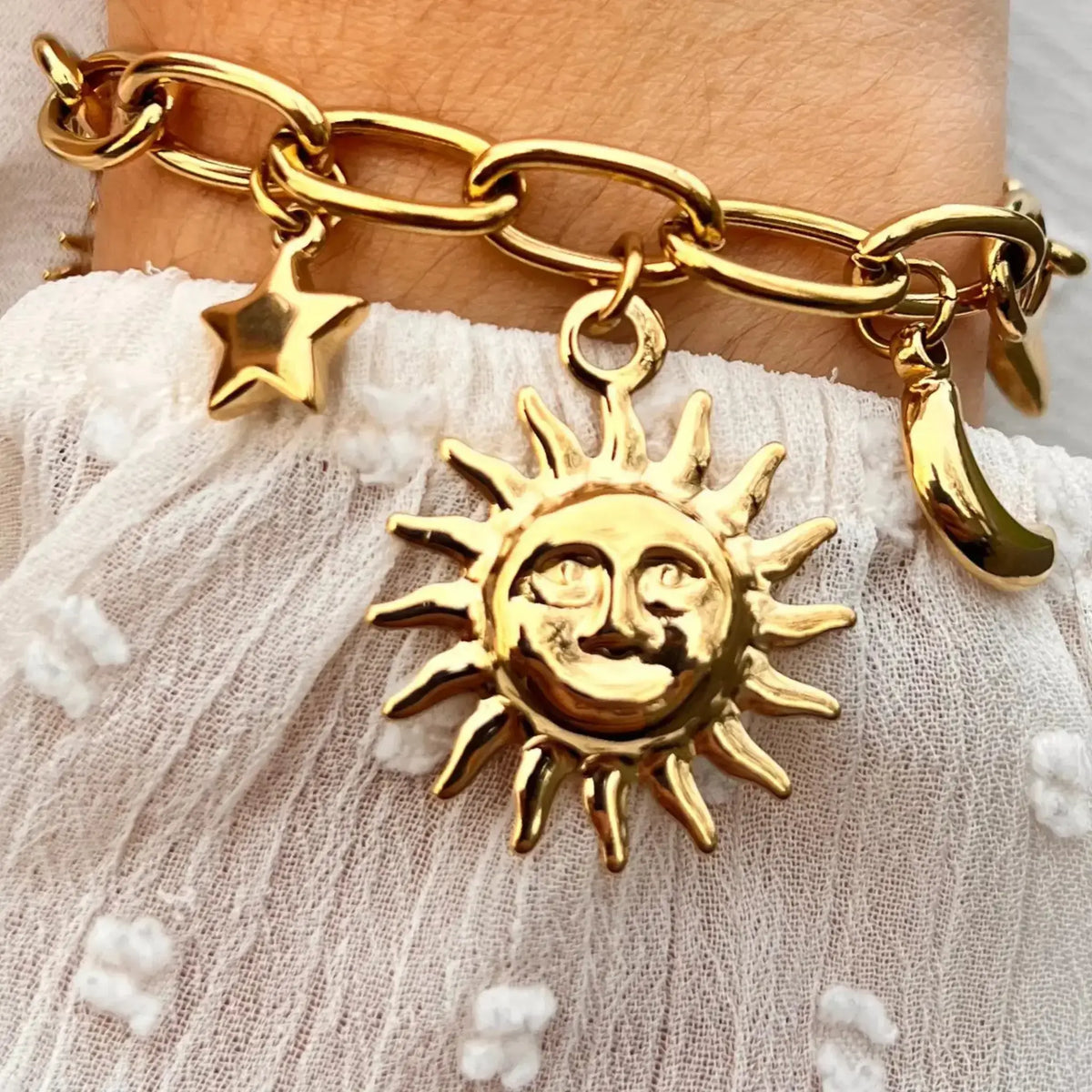 Bracelet Madrid doré porté, charms représentant les éléments célestes et le cœur, symbolisant la lumière et la passion de Madrid.