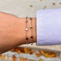 Bracelet Oslo en acier inoxydable argenté porté, design subtil avec étoiles et double chaîne, apportant une touche de sérénité et de modernité à votre poignet.