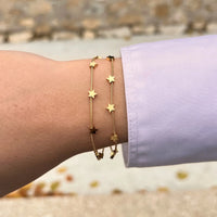 Bracelet Oslo doré porté, petites étoiles dispersées sur une double chaîne, capturant la clarté des cieux scandinaves avec élégance.