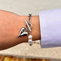 Bracelet Prague en acier inoxydable argenté porté, perles délicates et chaînes, avec charm cœur, parfait pour un look à la fois élégant et romantique.