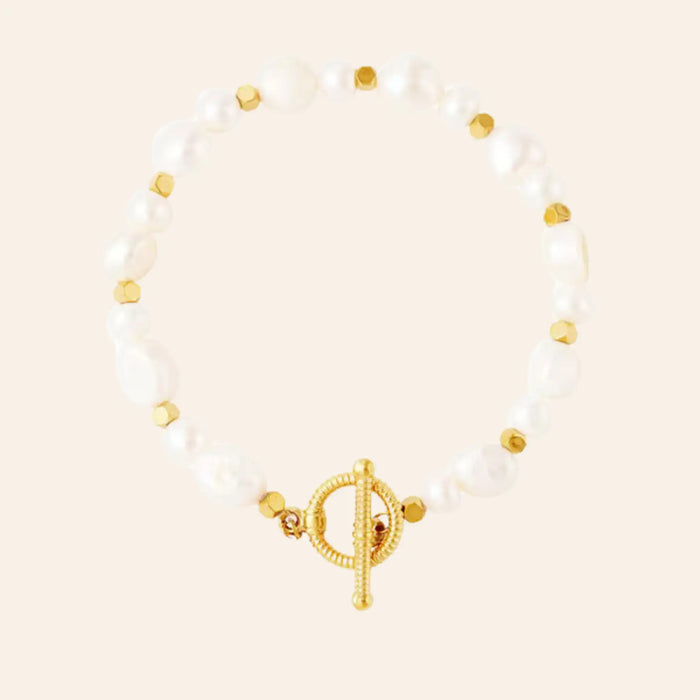 Bracelet Rabat en acier inoxydable doré, perles d'eau douce blanches irrégulières et détails dorés, design naturel et raffiné, présenté seul sur fond neutre.