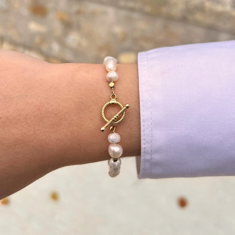 Bracelet Rabat doré porté, perles blanches irrégulières agencées avec soin, alliant l’artisanat traditionnel marocain à une touche moderne.