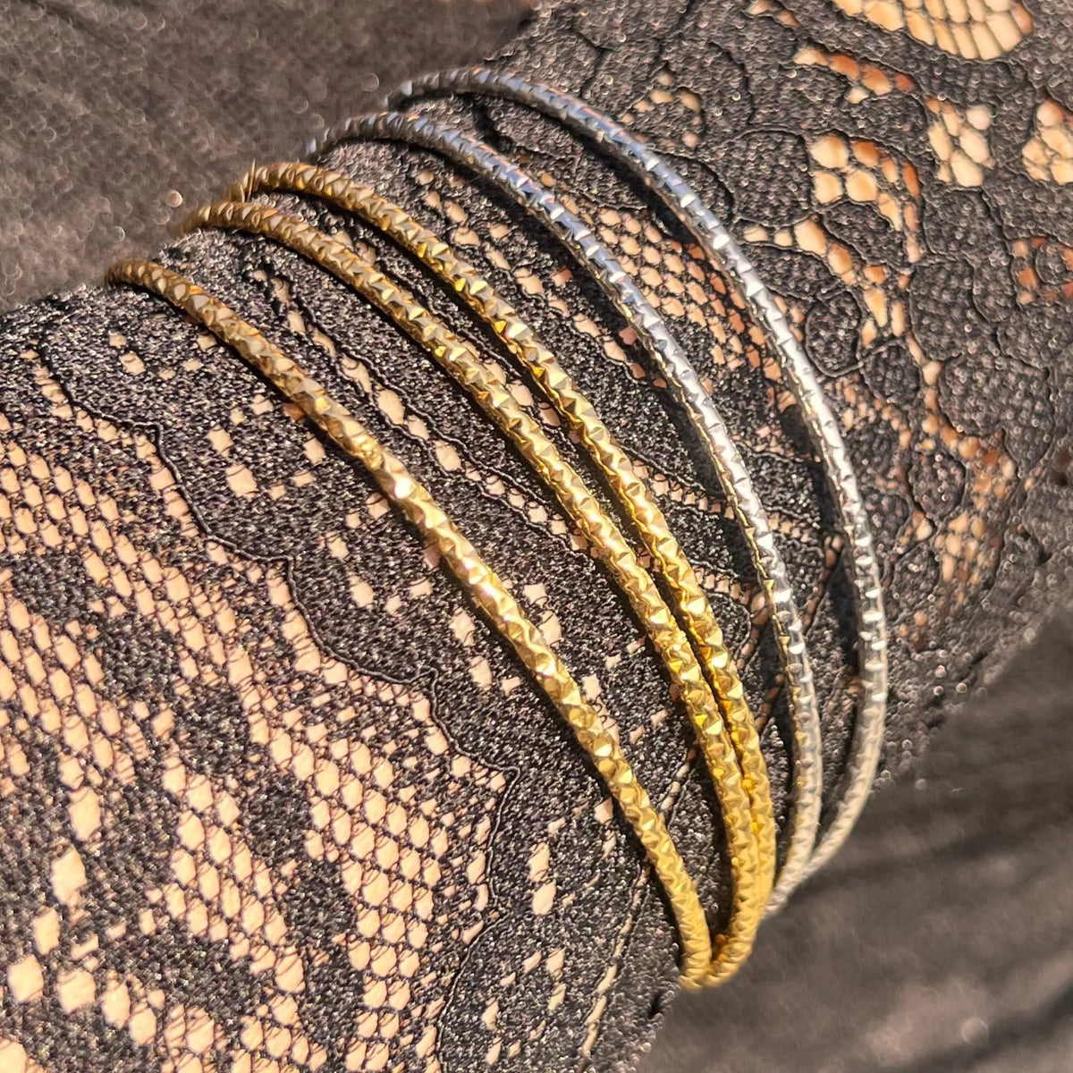 Poignet féminin orné du lot de 5 bracelets joncs Carthagène en acier inoxydable, mélange harmonieux de joncs dorés et argentés au design élégant.
