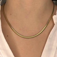 Collier Brasilia doré porté, chaîne délicate reposant élégamment sur le cou, parfait pour un look minimaliste et raffiné.