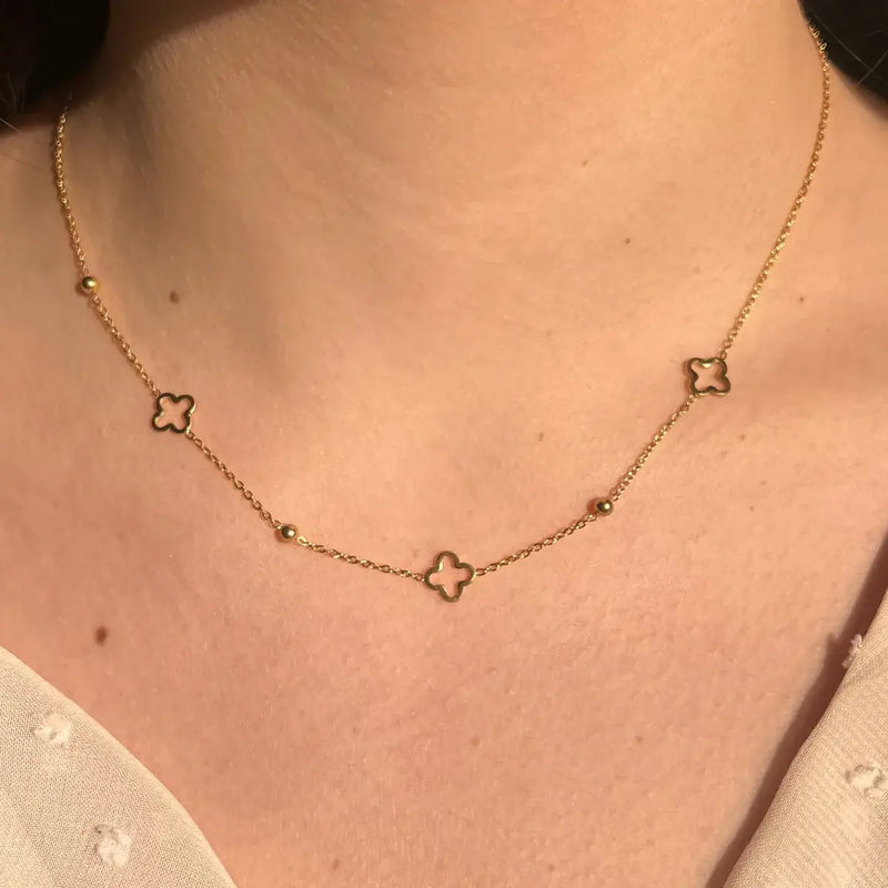 Collier Dublin doré porté, bijou élégant avec trèfles et boules espacées, ajoutant une touche raffinée à votre décolleté.