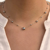 Collier Kyoto en acier inoxydable argenté porté, mettant en valeur l’espacement subtil des sphères et le design élégant.