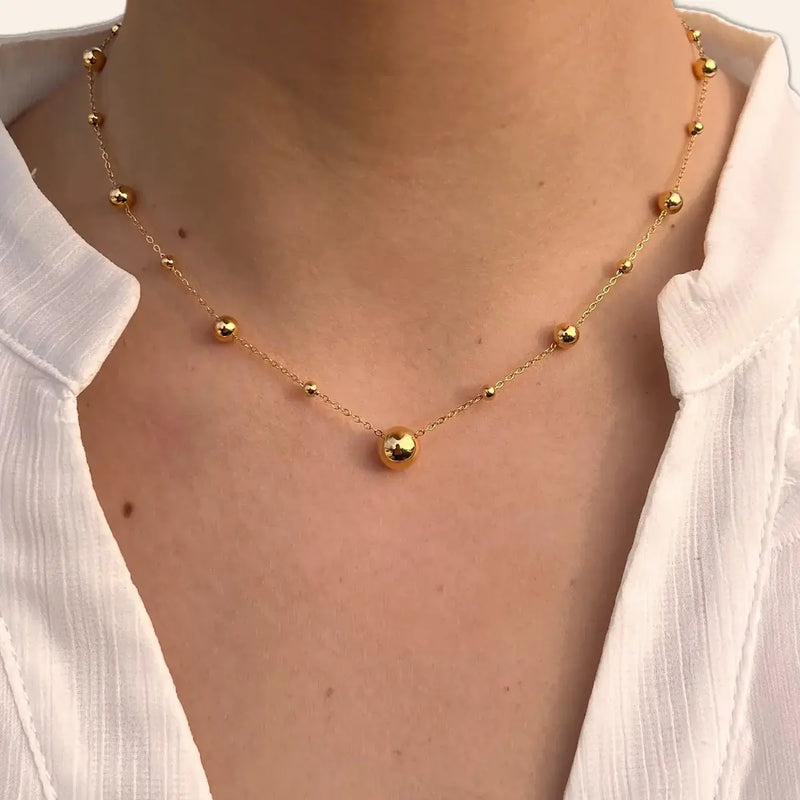Collier Kyoto doré porté, bijou raffiné avec sphères délicates ajoutant une touche de légèreté et d’élégance.
